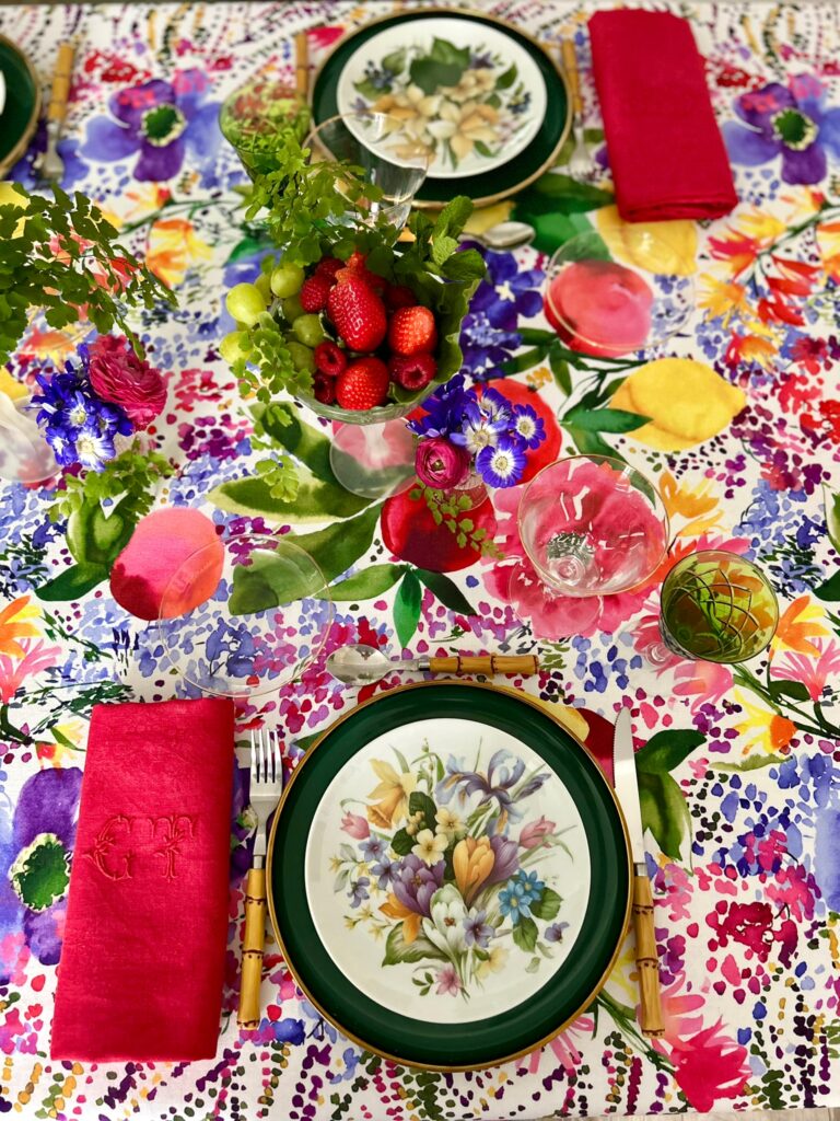 Allestimento primaverile con tovaglia a fiori e piatti in porcellana dipinta de La Tavola del Mese